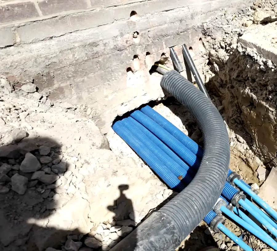 Blue water service ducts and a protective sleeve entering a building through its foundation