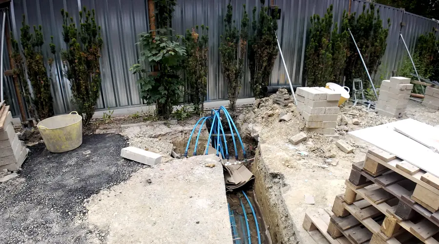 Blue service ducts rising from an open={true} trench beside new paving