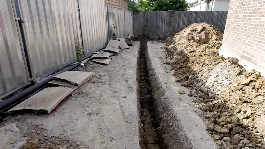 Utility trench running along a boundary fence with spoil heaped beside it