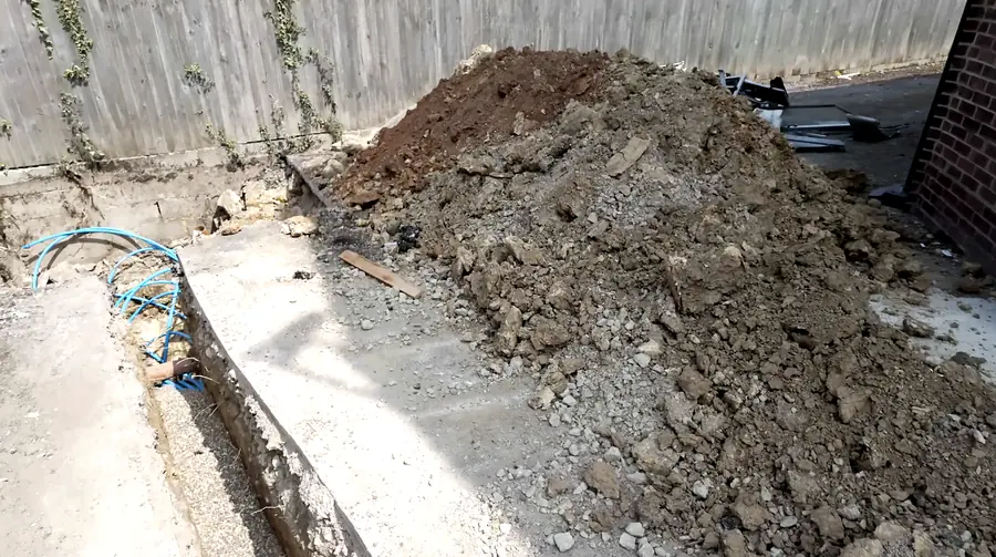 Excavated trench with blue duct coils and a spoil heap on a utility connection site